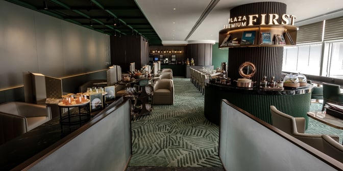 The Plaza Premium First lounge near Gate 35 at Hong Kong International Airport features a seating area with a bar and self-serve food stations.