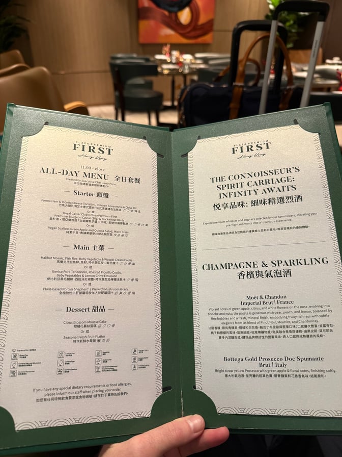 A menu from Plaza Premium First lounge at Hong Kong International Airport lists all-day dining options and champagne selections.