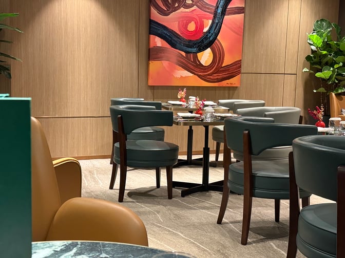 The seating area in Plaza Premium First lounge at Hong Kong International Airport features tables set for dining with comfortable chairs.