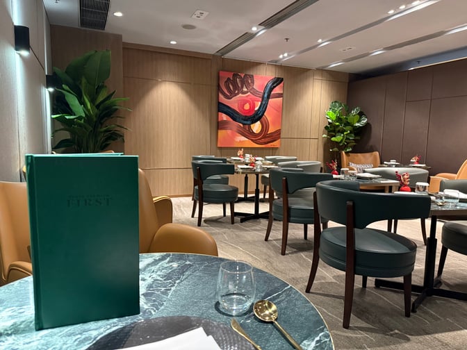 The Plaza Premium First lounge near Gate 1 at Hong Kong International Airport features a seating area with tables set for dining.