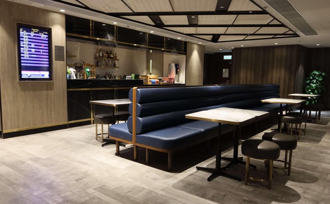 The Plaza Premium First lounge near Gate 1 at Hong Kong International Airport features booth seating and a bar.
