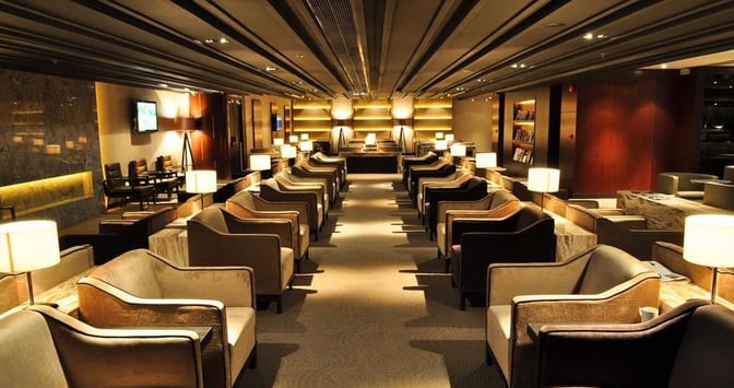 The seating area in Plaza Premium First Lounge at Hong Kong International Airport features rows of armchairs with individual lamps and tables.