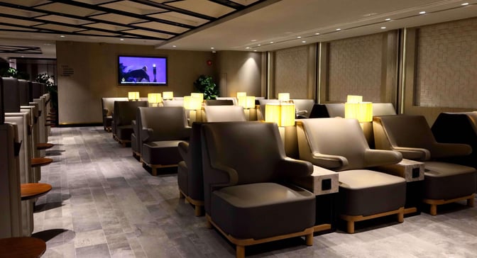 The seating area in Plaza Premium First Lounge at Hong Kong International Airport offers comfortable chairs with individual lamps and side tables.