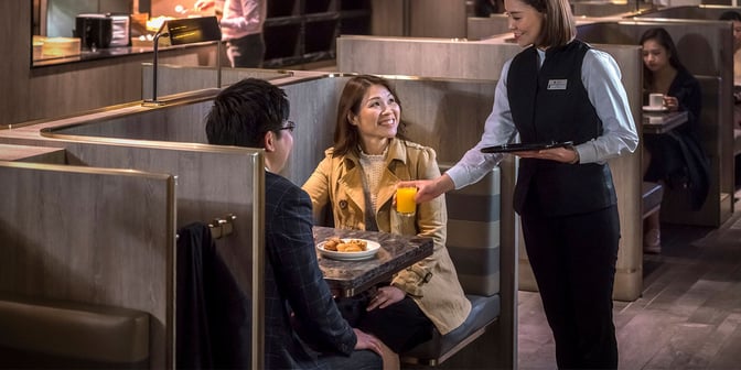 Booth seating in the Plaza Premium Lounge at Hong Kong International Airport offers semi-private dining with table service near Gate 1.