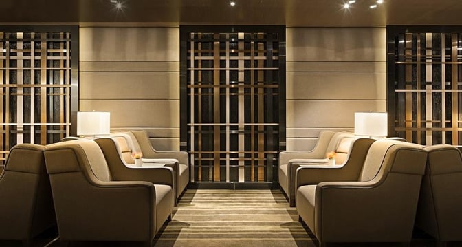 The seating area in Plaza Premium Lounge near Gate 35 at Hong Kong International Airport features armchairs and small tables with lamps.