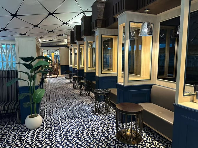 The seating area in Club Autus at Hong Kong International Airport features booth seating with small tables and decorative partitions.