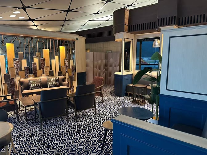 The seating area in Hong Kong Airlines Lounge features comfortable chairs and tables, with decorative partitions providing a semi-private atmosphere.