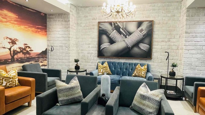 The seating area in Paragon Premium Lounge at Hosea Kutako International Airport features comfortable chairs and couches with decorative artwork.