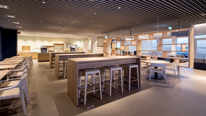 The Hugo Junkers Lounge at Dusseldorf Airport features communal tables and seating areas with a self-serve food and beverage station.