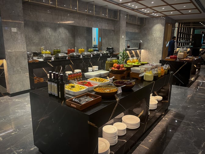 The Encalm Lounge at Indira Gandhi International Airport features a buffet area with a variety of self-serve food options and condiments.