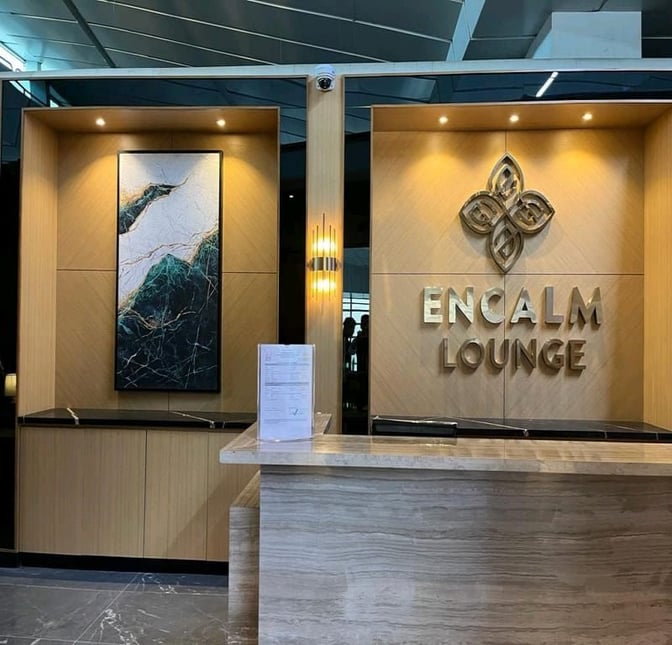 The Encalm Lounge entrance at Indira Gandhi International Airport features a reception desk and decorative wall art.