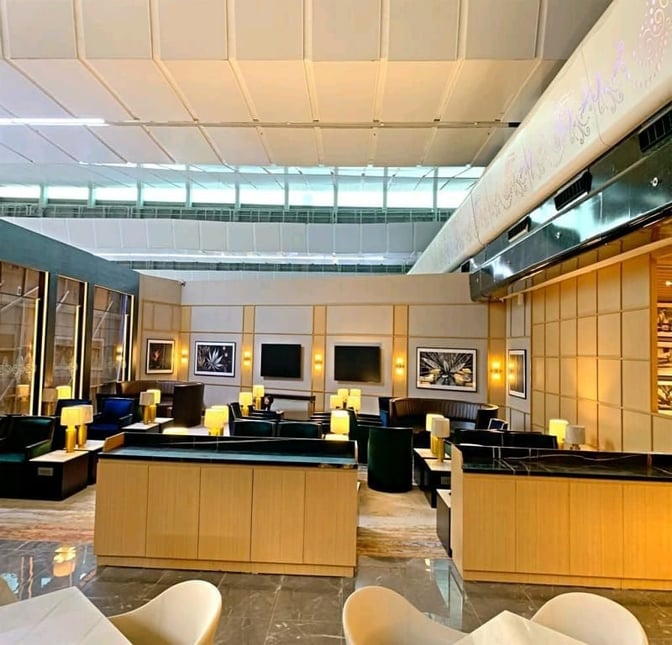 Seating area in Encalm Lounge at Indira Gandhi International Airport features comfortable chairs and tables with wall art and ambient lighting.