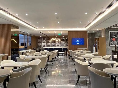 The seating area in Encalm Lounge at Indira Gandhi International Airport features numerous tables and chairs for dining and relaxation.