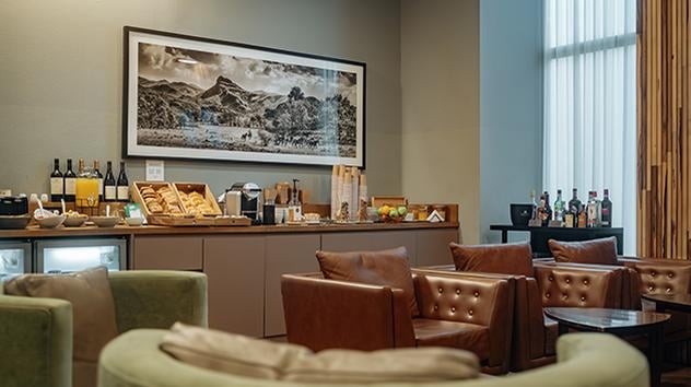 The lounge at Cordoba Airport features a seating area with leather chairs and a self-serve snack and beverage station.