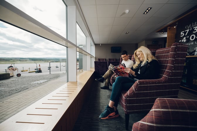 Seating area in Aspire Lounge at Inverness Airport offers comfortable chairs with views of the runway through large windows.