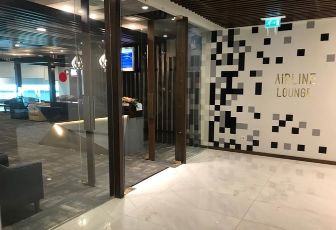 The entrance to the Airline Lounge at Islamabad International Airport features glass doors and a wall with the lounge's name.