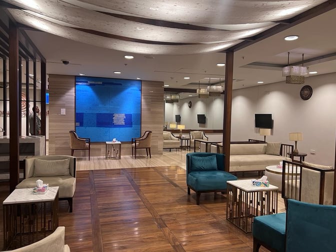 The Domestic CIP Lounge at Islamabad International Airport features comfortable seating areas with tables, offering a relaxing space for travelers.