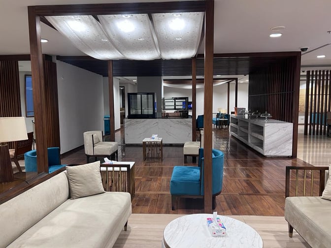 The Domestic CIP Lounge at Islamabad International Airport features comfortable seating areas with tables and a self-serve refreshment counter.