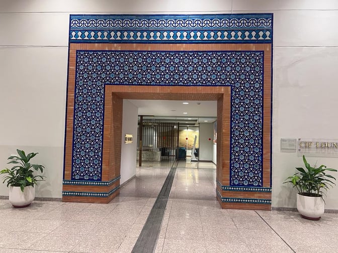 The entrance to the CIP Lounge at Islamabad International Airport features a decorative archway with patterned tiles and potted plants.