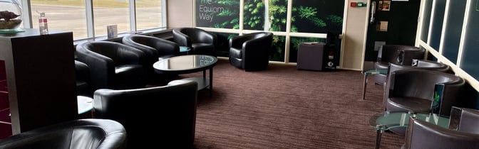 The Rendezvous Lounge at Isle of Man Airport offers comfortable seating with round tables and views of the tarmac.