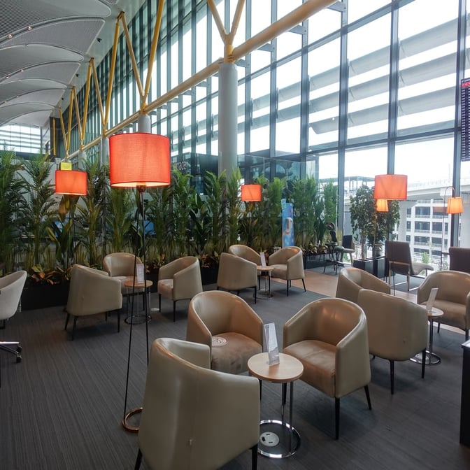 The seating area in the IGA Lounge at Istanbul Airport features comfortable chairs and tables with views of the airport.