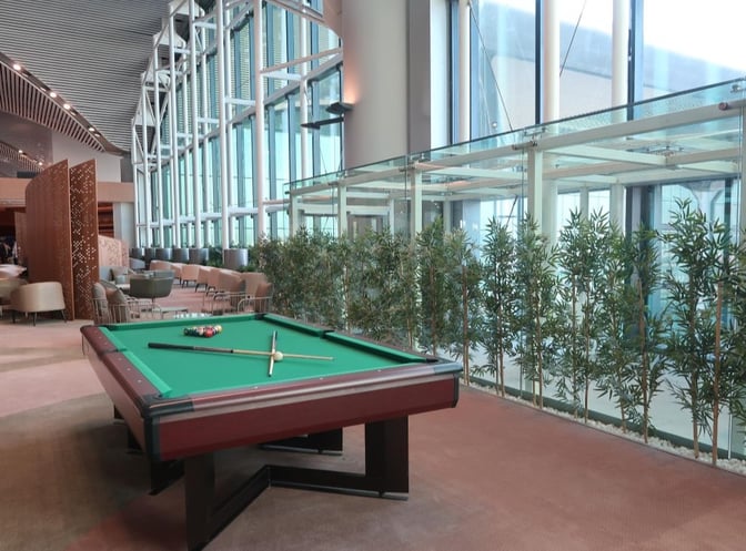The IGA International Lounge at Istanbul Airport features a billiards table and seating area with large windows and greenery.