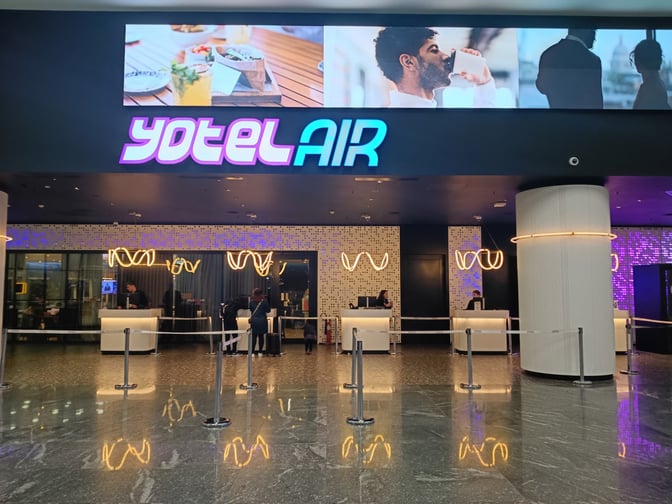 The entrance to YotelAir at Istanbul Airport features a reception area with check-in counters and a queue system for guests.