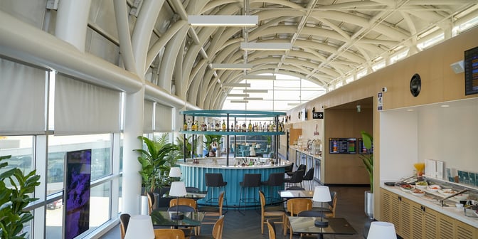 The Primeclass Lounge at Izmir Airport features a central bar with seating and a self-serve food area offering various dishes.