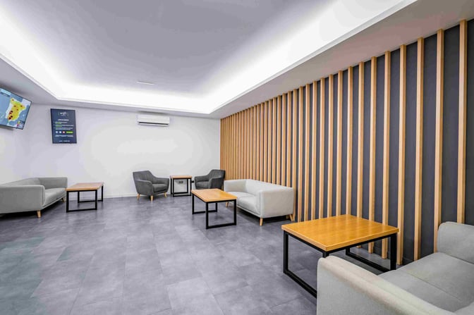 The seating area in Jable VIP Lounge at Fuerteventura Airport features comfortable chairs, sofas, and tables with wall-mounted screens.