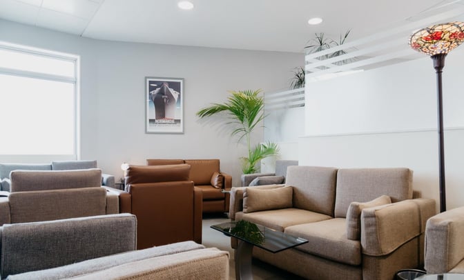 The Executive Lounge at Jersey Airport features comfortable seating with sofas and armchairs, complemented by a decorative floor lamp and plants.