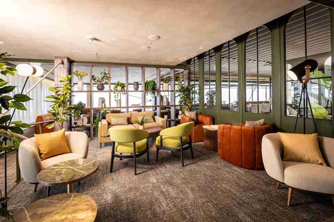 The seating area in No1 Lounge Jersey at Jersey Airport features comfortable chairs and sofas with tables for relaxation.