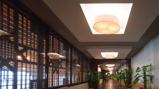 The corridor of the marhaba Lounge at Jinnah International Airport features decorative ceiling lights and potted plants along the walkway.