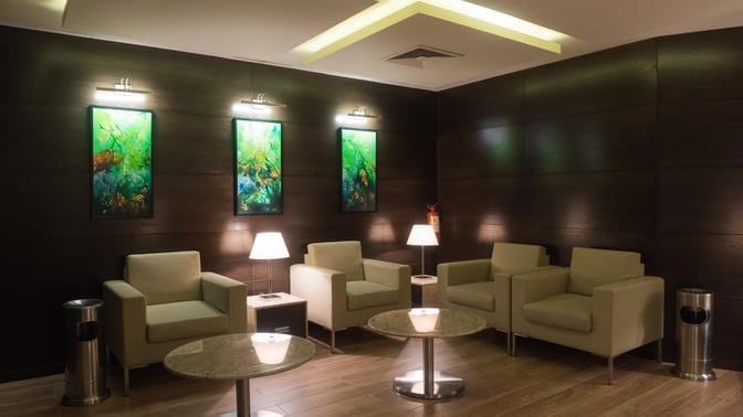 Seating area in the marhaba Lounge at Jinnah International Airport features armchairs, small tables, and decorative wall art.