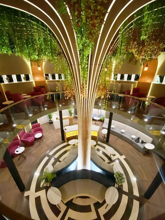 The Sky Majestic Lounge at Jinnah International Airport features a two-level seating area with circular arrangements and hanging greenery.
