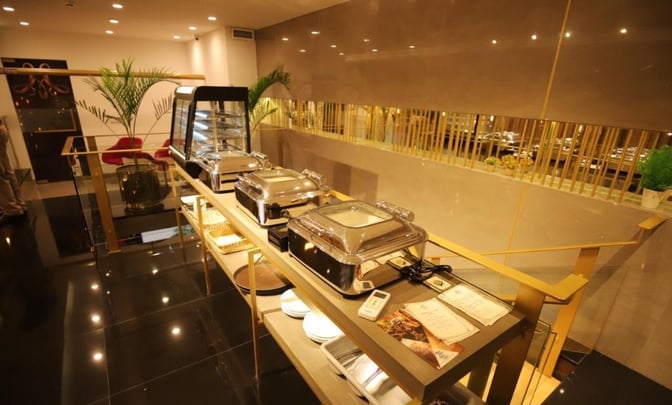 Buffet area at Majestic Lounge, Jinnah International Airport, features self-serve chafing dishes and a display case for hot and cold meals.
