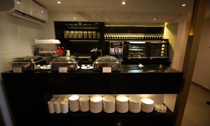 The Majestic Lounge at Jinnah International Airport features a self-serve food station with hot dishes, coffee machine, and ample dishware.