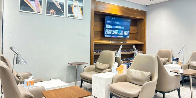 Seating area in Hayyak Lounge at King Abdullah bin Abdulaziz International Airport features comfortable chairs, individual lamps, and a wall-mounted TV.