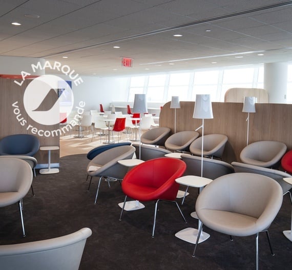 The Air France Lounge at JFK Airport features a seating area with individual chairs, small tables, and nearby dining tables.