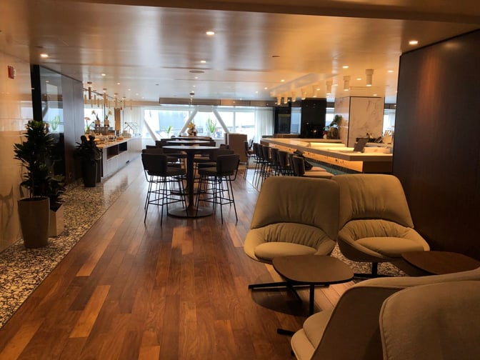 The Primeclass Lounge at JFK Airport features a seating area with comfortable chairs and tables, adjacent to a bar and dining space.