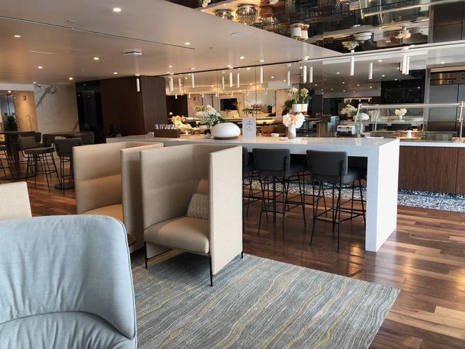 The Primeclass Lounge at JFK Airport features booth seating and a bar area with high stools for dining and refreshments.