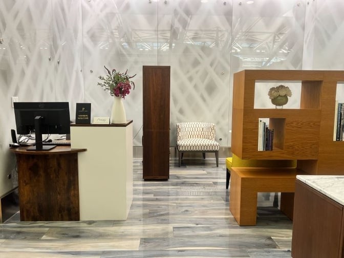 The VIP One lounge at JFK Airport features a reception desk with a computer and a seating area with a decorative partition.