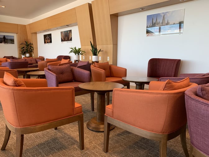 Seating area in the Air India Maharajah Lounge at JFK Airport features comfortable chairs and tables for relaxation and conversation.