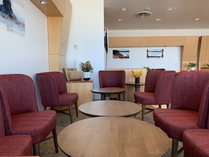 Seating area in the Air India Maharajah Lounge at JFK Airport features round tables and chairs, providing a comfortable waiting space.