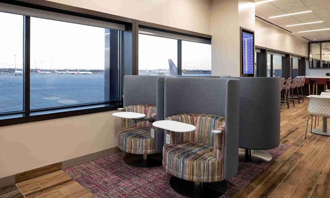 Semi-private seating at the Escape Lounge in Port Columbus International Airport offers individual chairs with small tables and airport views.