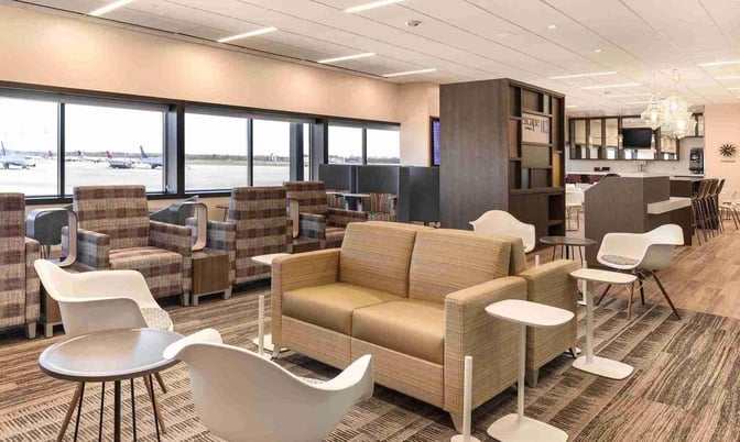 The seating area at Escape Lounge, Port Columbus International Airport, features comfortable chairs and tables with views of the runway.