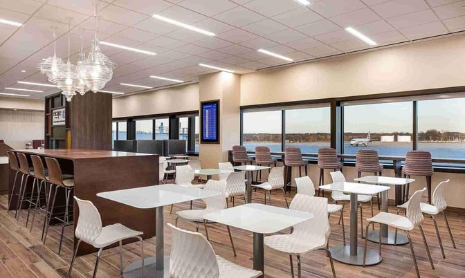 The seating area in the Escape Lounge at Port Columbus International Airport offers tables and chairs with views of the runway.