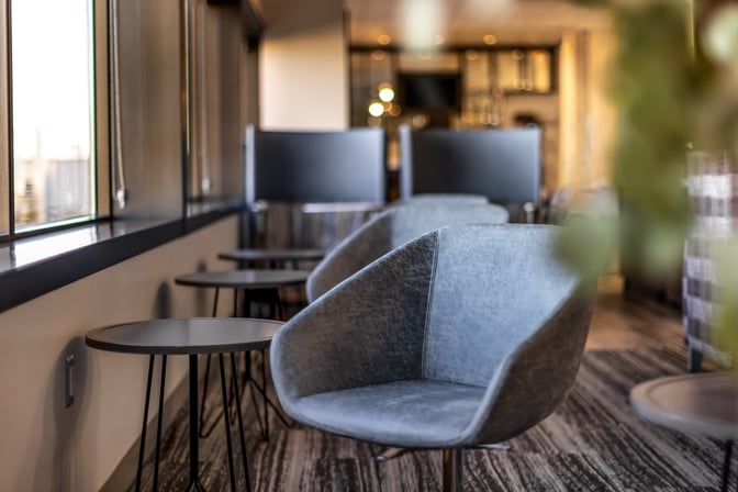 Seating area in the Escape Lounge at Port Columbus International Airport features comfortable chairs and small tables with window views.