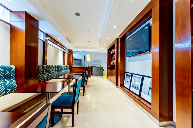 Booth seating in the Aspire Lounge at Jomo Kenyatta International Airport offers semi-private dining with tables and a television.