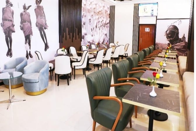 The Asante Lounge at Jomo Kenyatta International Airport features a seating area with tables, chairs, and decorative wall art.