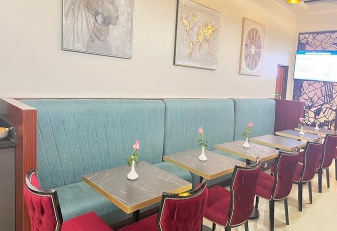 Booth seating in Asante Lounge at Jomo Kenyatta International Airport offers semi-private dining with small tables and decorative wall art.